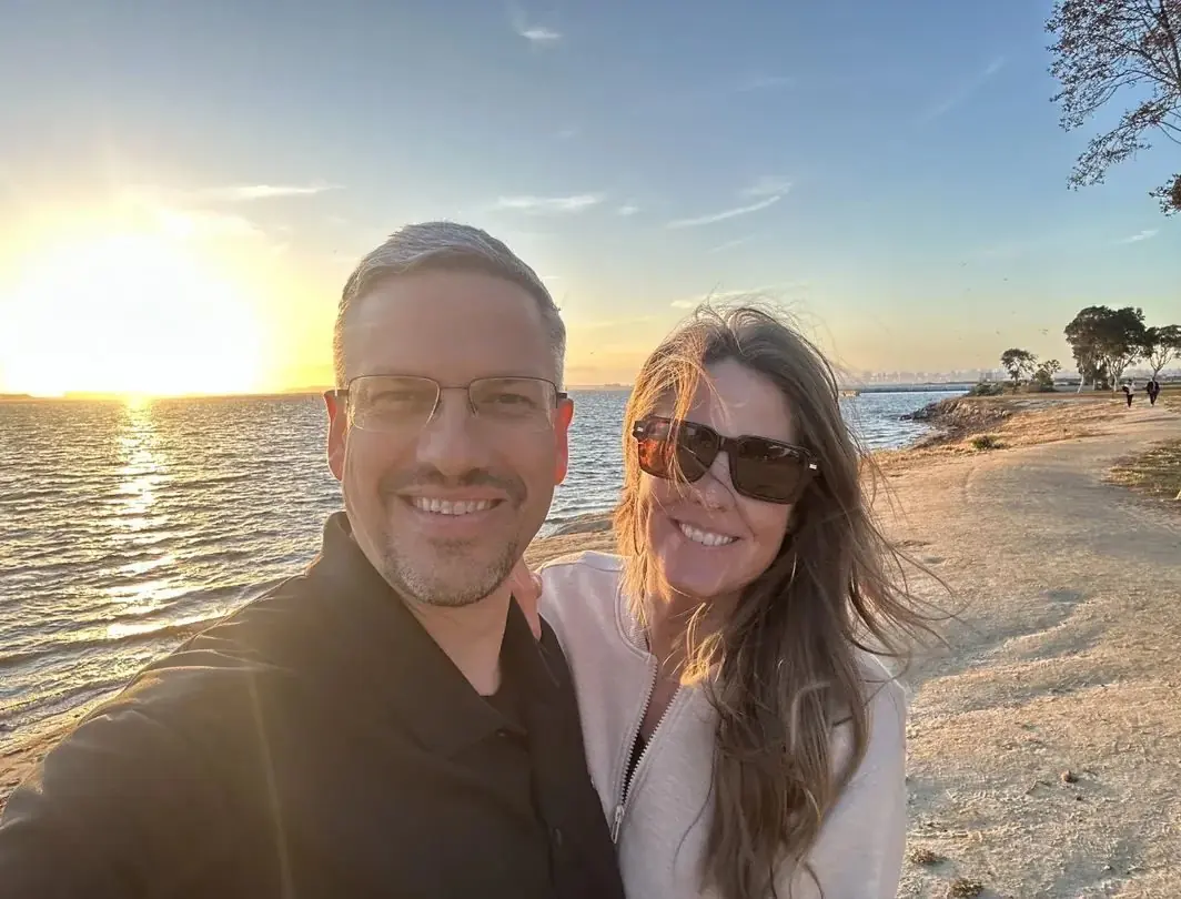 Stacey and Brad Shannon smiling on a waterfront path at sunset.